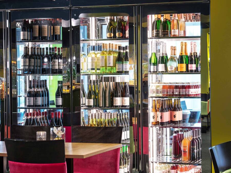 Una zona de bar con varias estanterías llenas de botellas de vino y copas.