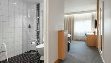 A hotel bathroom with a shower, toilet, and sink.