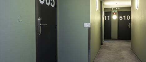 Ein Flur mit Türen mit den Nummern 505 und 510, mit Teppichböden und runden Leuchten an der Wand.