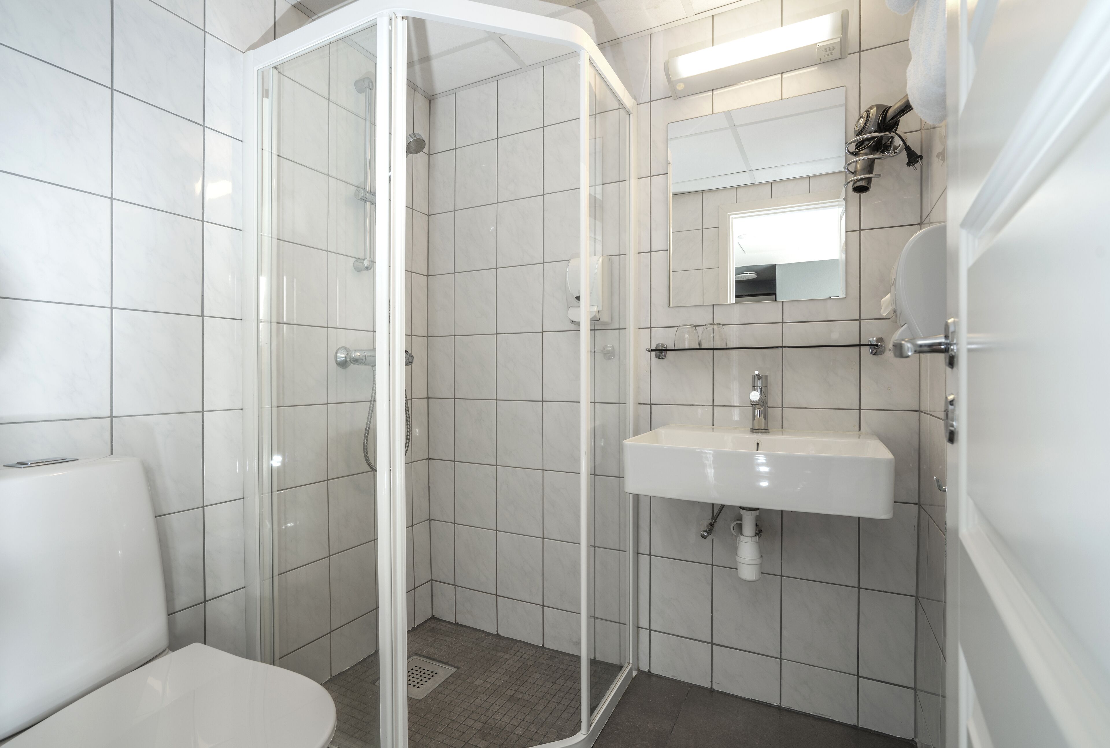 A modern bathroom with a glass-enclosed shower, a white sink, and a toilet.
