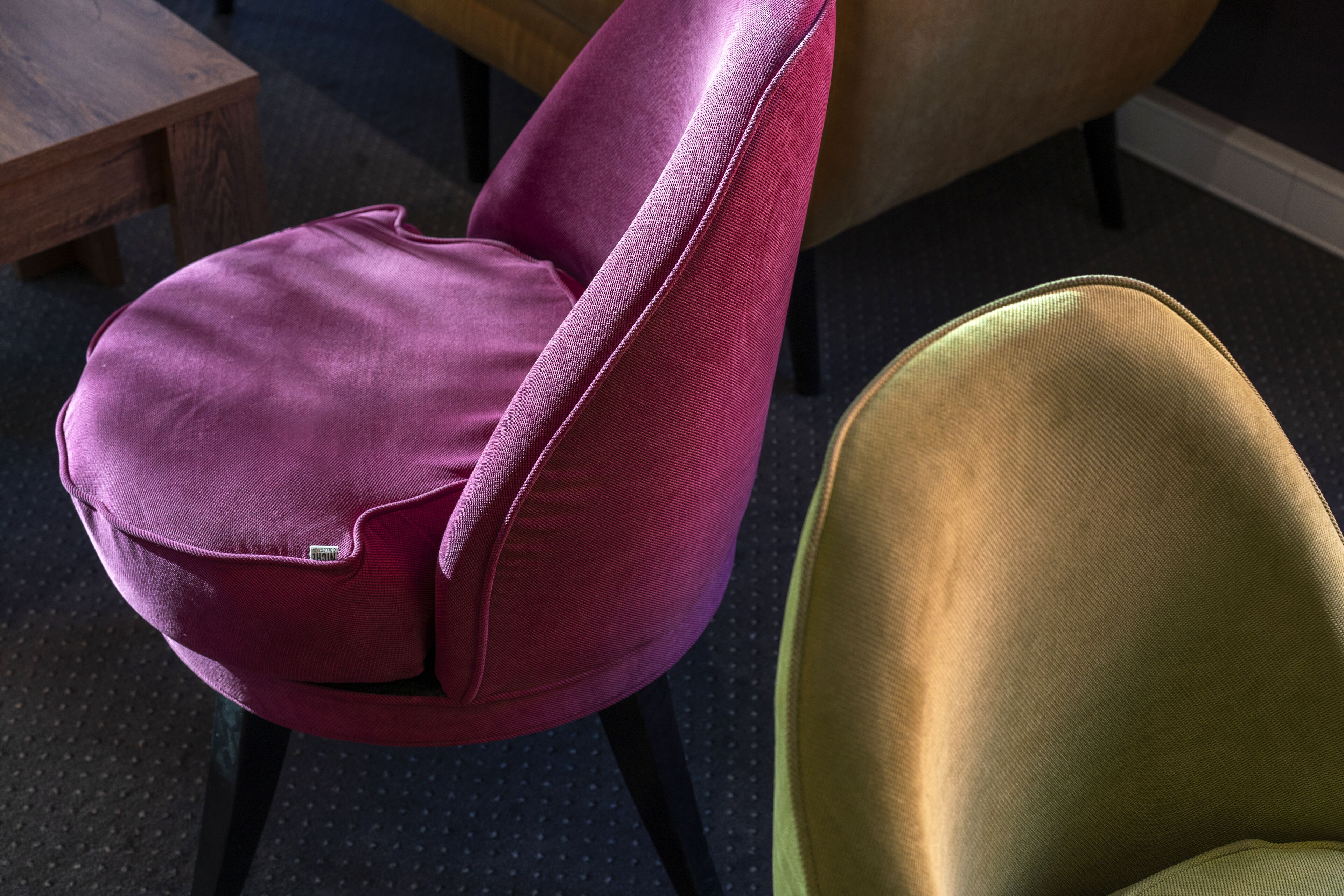 Primer plano de una silla morada con respaldo alto y una silla verde con respaldo curvo.