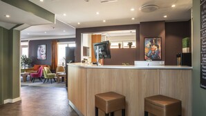 A modern reception area with a wooden counter, two stools, and a large screen. - Thon Hotel Storgata (Kristiansund)