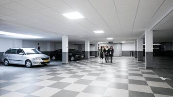 Un estacionamiento con suelo a cuadros, pilares blancos y varios coches aparcados.