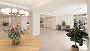 A spacious lobby with a round wooden table, a large potted plant, and a modern chandelier. - Hotel Best Auto Hogar (Barcelona)