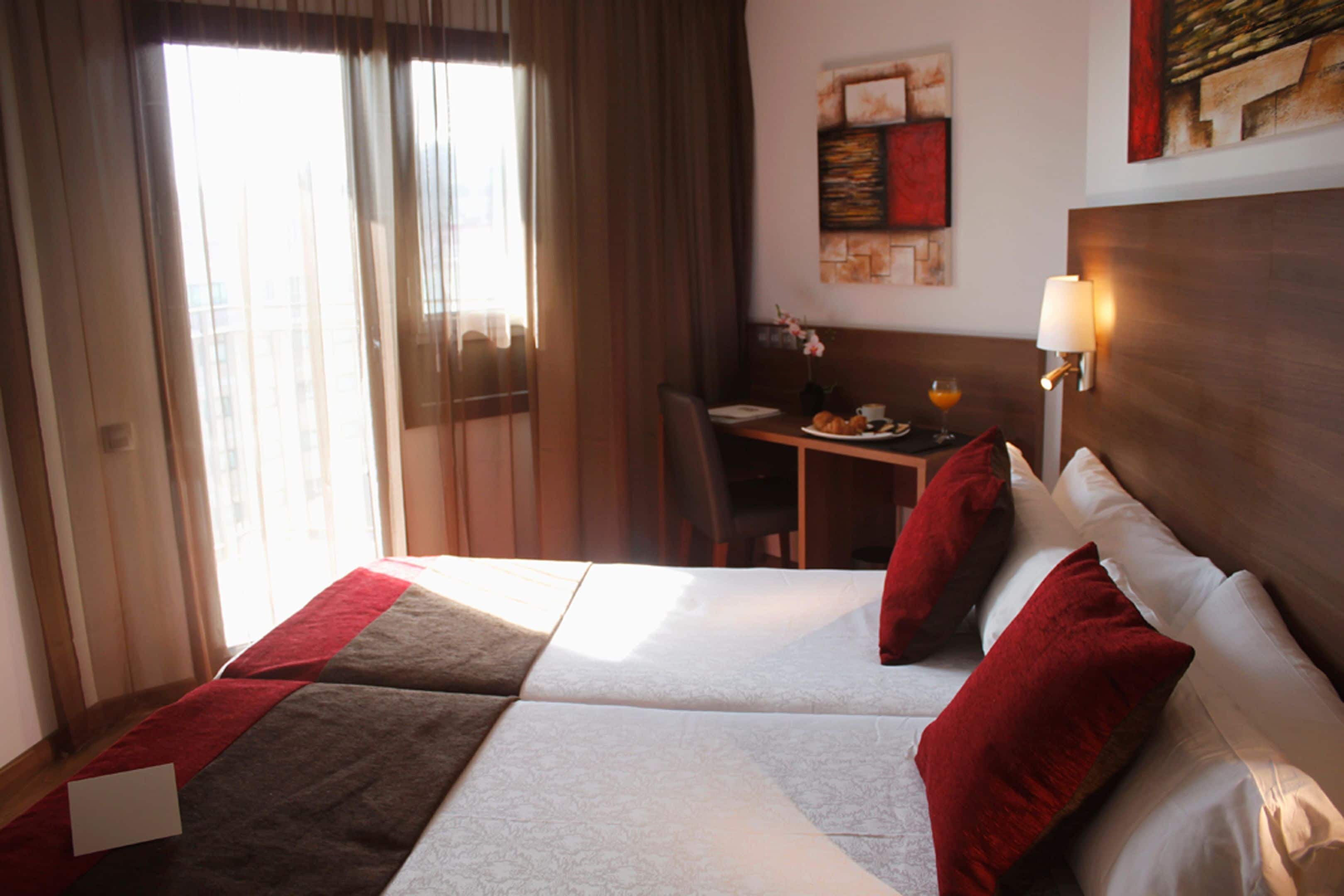 Una habitación de hotel con cama, escritorio y lámpara.
