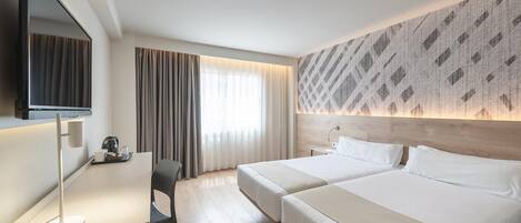 Habitación de hotel con dos camas, un escritorio, un televisor y un ventanal con cortinas.