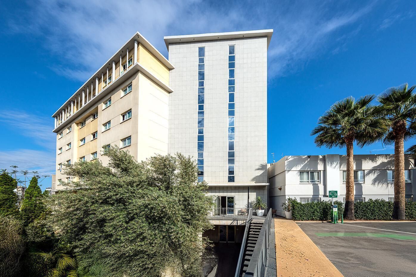 A modern hotel with a central tower and a shorter building on the left.