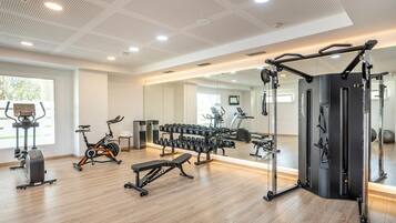 Un gimnasio moderno con equipo cardiovascular, máquinas de pesas y un espejo grande.