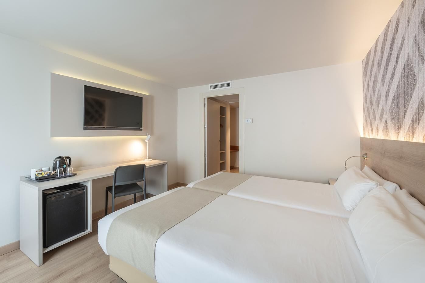 Une chambre d’hôtel comprenant un lit, un bureau avec une chaise, une télévision et une armoire.