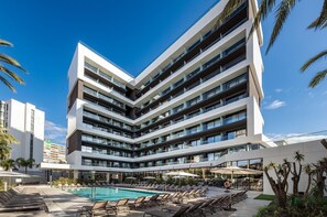 A modern hotel with multiple balconies, a swimming pool, and outdoor seating areas. - Hotel Port Alicante City & Beach (Alicante)