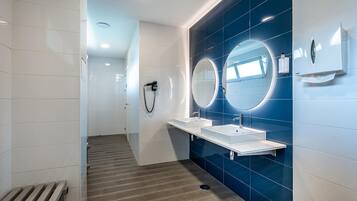 A modern bathroom with two sinks, large mirrors, and a shower area.