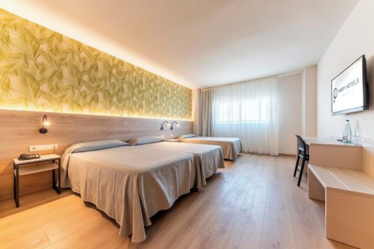 A hotel room with two beds, a desk, a chair, and a TV.