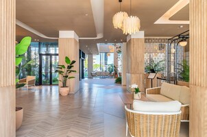 Un hall d ’entrée moderne avec un parquet en chevrons, des meubles en osier et de grandes plantes en pot.