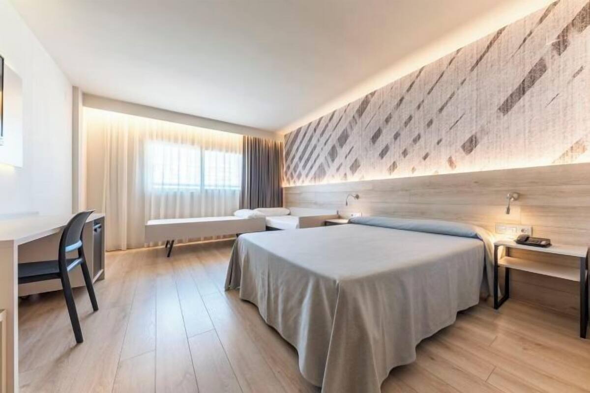 Una habitación de hotel moderna con una cama grande, un escritorio y una silla.
