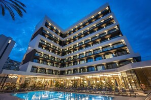 Ein mehrstöckiges Hotel mit Schwimmbereich vor der Fassade.
