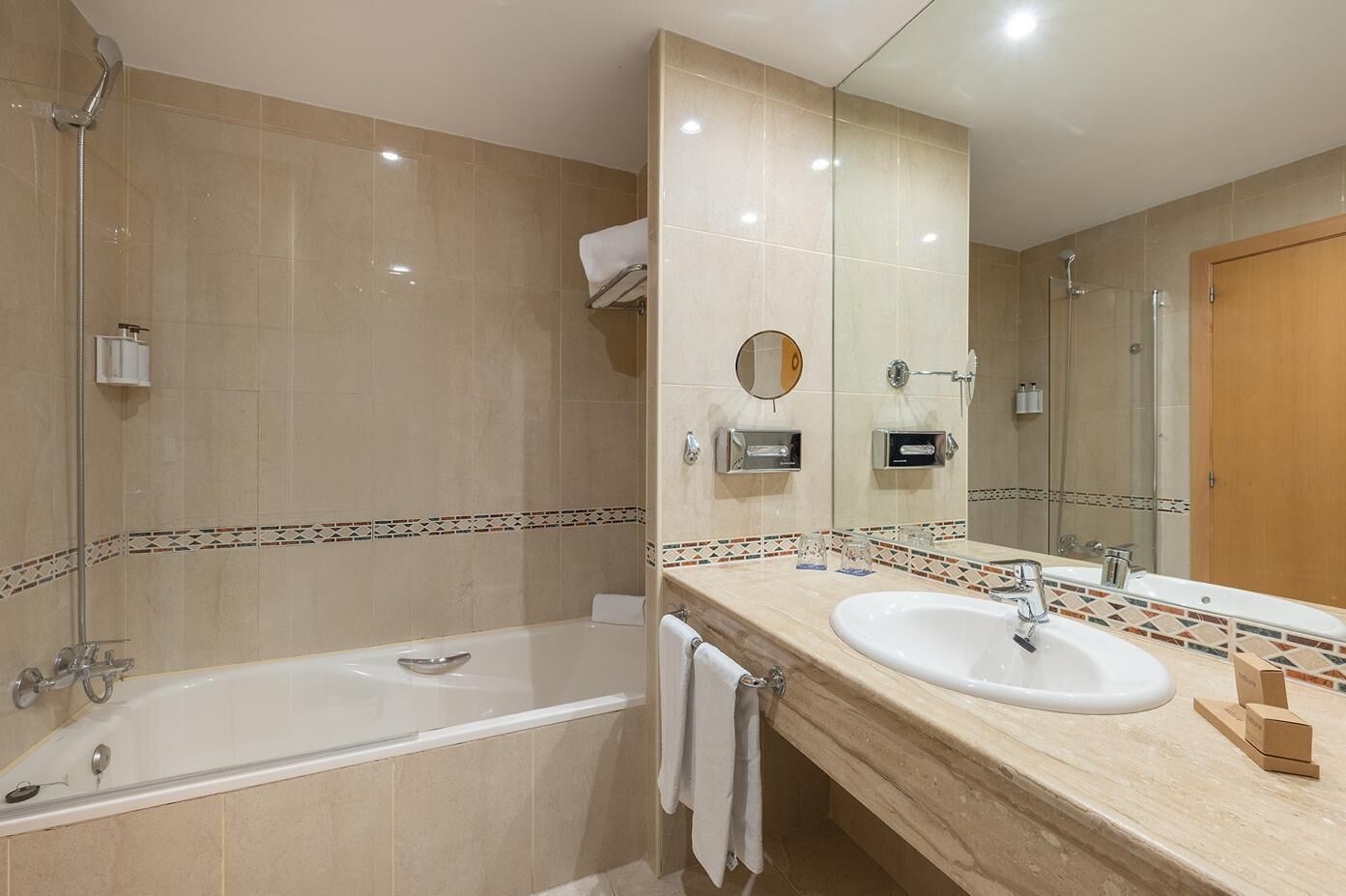 Un baño moderno con bañera, dos lavamanos, un espejo grande y ducha.