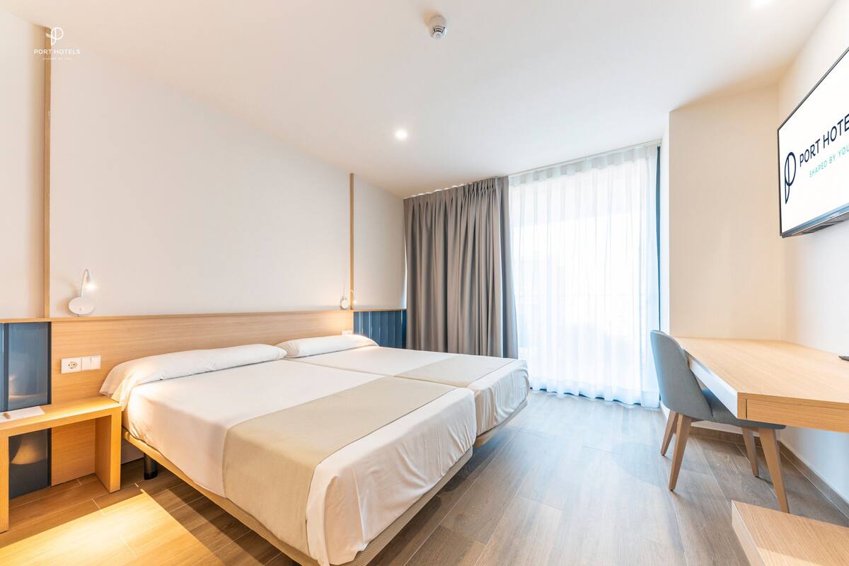 Una habitación de hotel con una cama grande, un escritorio, una silla y un televisor sobre un mueble.