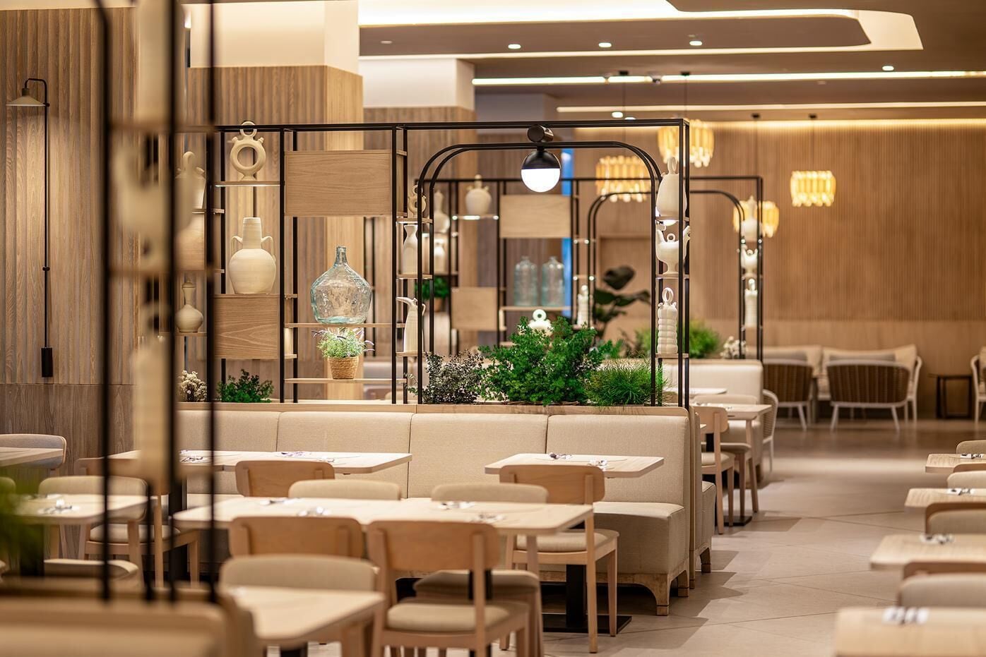Een modern restaurantinterieur met zitjes en tafels, houten wandpanelen en decoratieve verlichting.