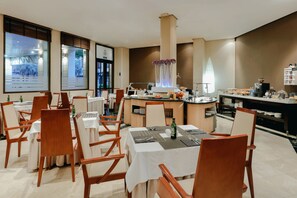 A dining area with tables set for guests, a coffee station, and a view of the outside. - Hesperia Zaragoza Centro (Zaragoza)