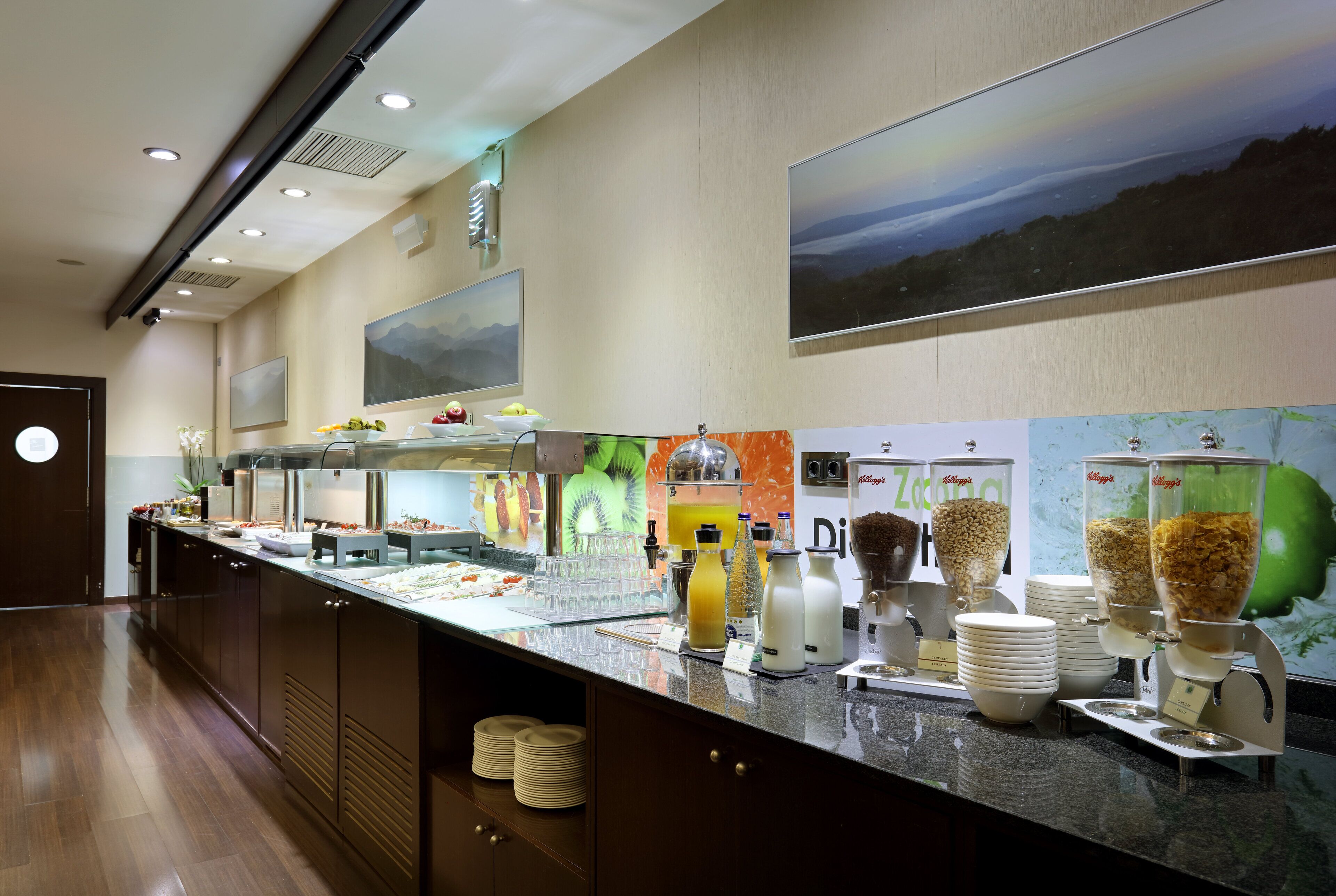 A buffet area with various food stations, including a fruit display and beverage dispensers.