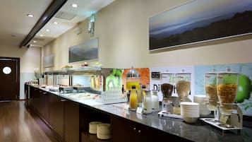 A buffet area with various food stations, including a fruit display and beverage dispensers.