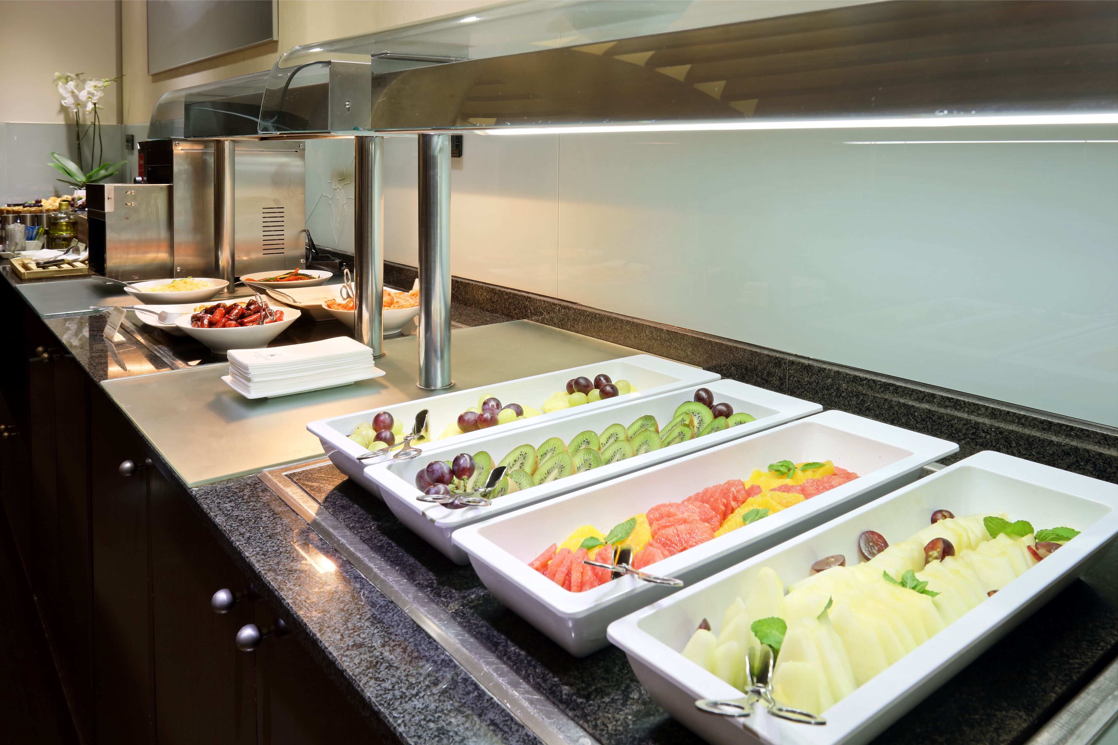 Un buffet proposant une variété de fruits et de légumes présentés dans des plateaux.