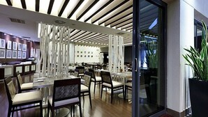 A modern dining area with tables and chairs, a decorative ceiling, and a large window with a view.