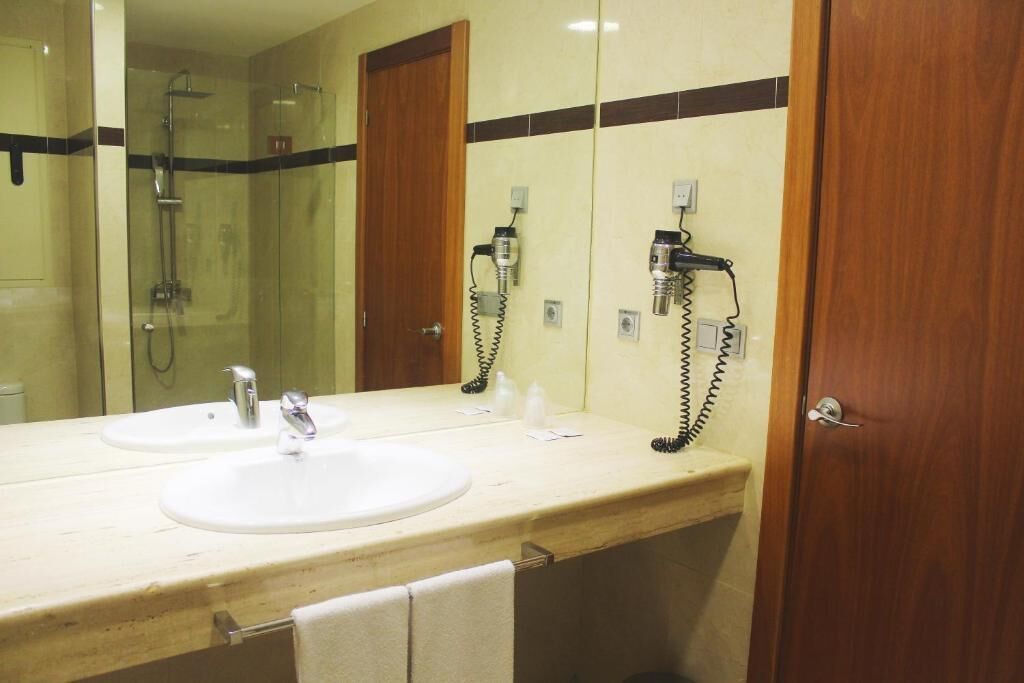 Une salle de bain avec deux lavabos, une douche et un miroir.