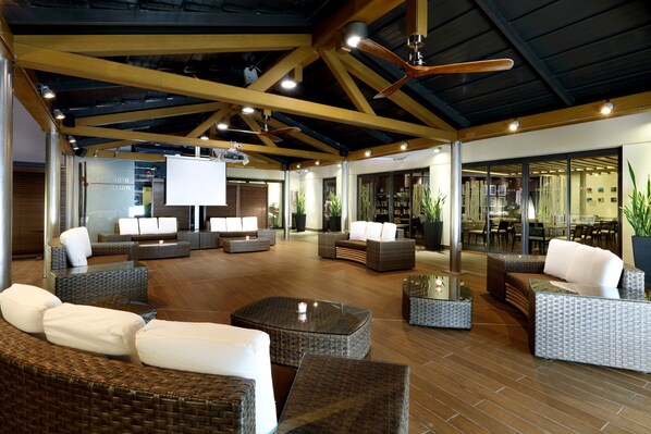 A spacious lobby with wicker furniture, a large screen, and a ceiling with exposed beams and lighting. - Eurostars Centrum Alicante (Alicante)