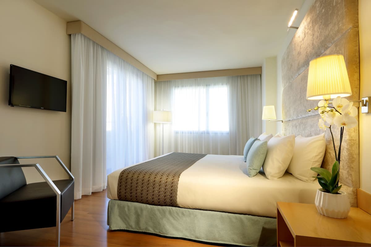 Een hotelkamer met een bed, een televisie, een bureau en een lamp.