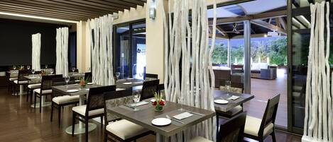 Un comedor moderno con mesas y sillas, vistas al exterior y un diseño interior contemporáneo.