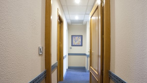 A hallway with wooden doors, a blue carpet, and a framed artwork on the wall. - Espahotel Gran Via (Madrid)