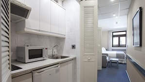 A compact hotel room with a kitchenette, a sink, a microwave, and a small dining area with a table and chair. - Espahotel Gran Via (Madrid)