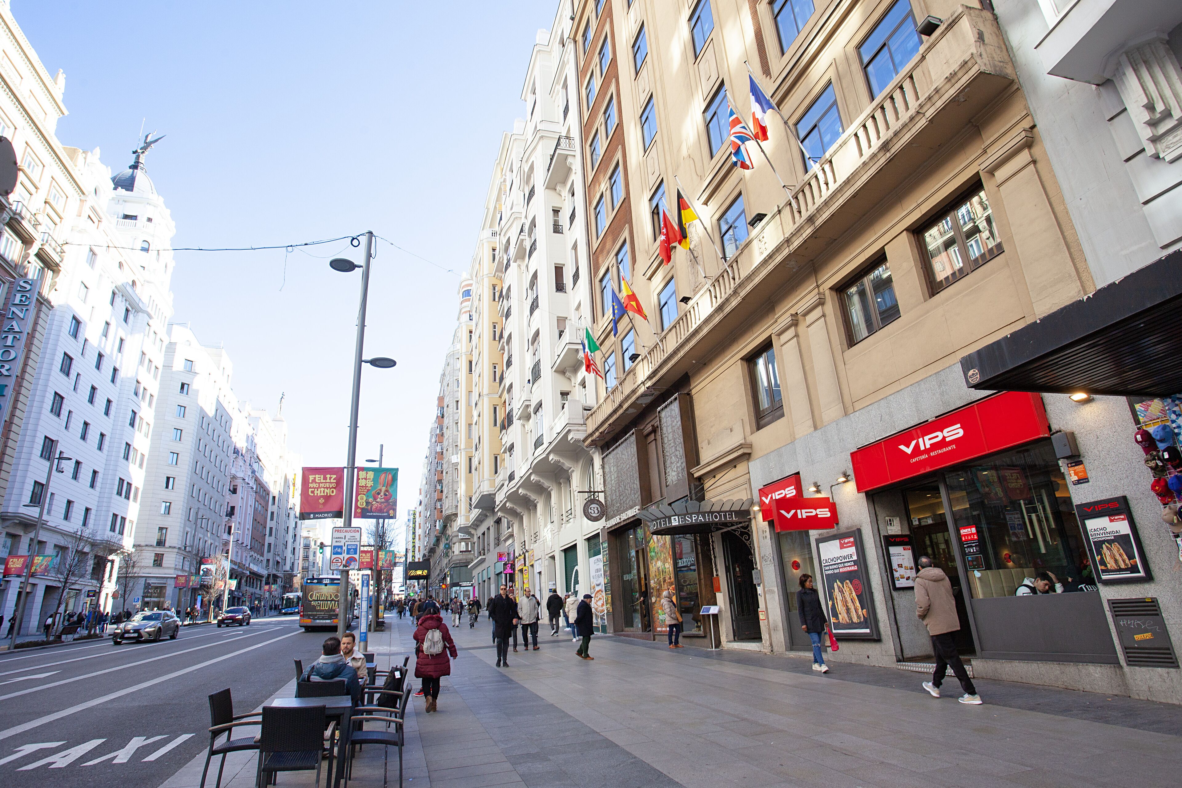 A city street with a hotel named 'VIPS' on the right, featuring a red awning and a signboard.