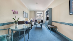 A hotel room with a glass table, a sofa, a bench, and a TV. - Espahotel Gran Via (Madrid)
