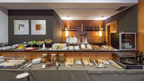 A buffet setup with various food items, a refrigerator, and a wine rack. - Hotel Yoldi (Pamplona)