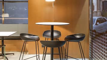 Un interior moderno con una mesa redonda, cuatro sillas negras e iluminación colgante.