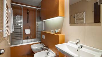 A modern bathroom with a shower, toilet, bidet, and sink.