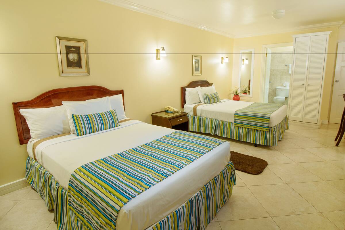 A hotel room with two beds, a bathroom, and a closet.