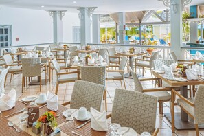 A spacious dining area with multiple tables and chairs, each set with white tableware and napkins.