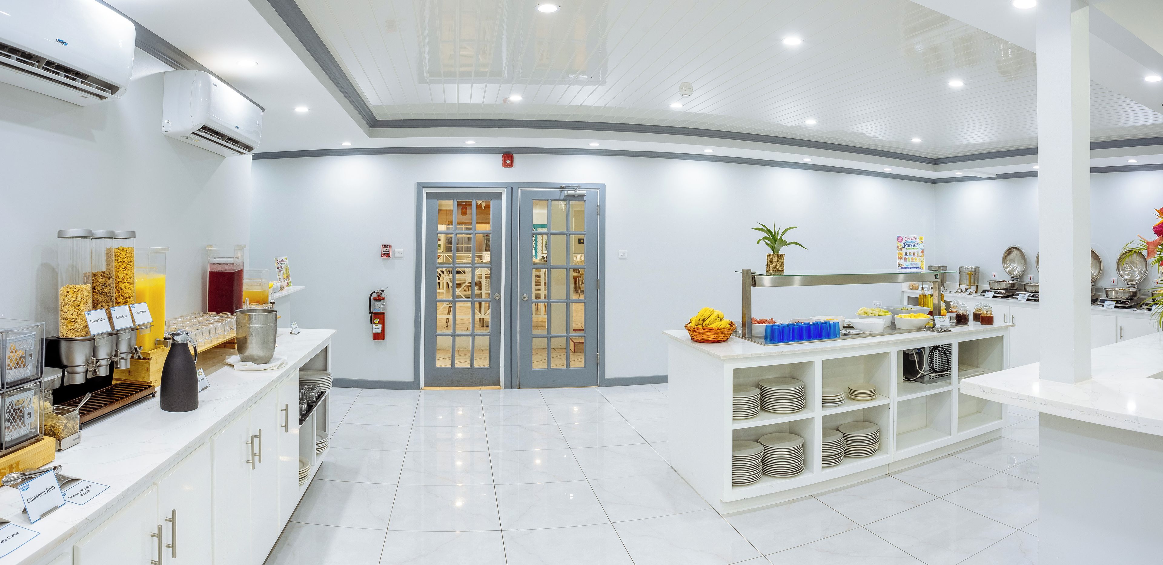 Quarto de hotel limpo e bem iluminado com bancada para café da manhã, minibar e vista para o exterior.