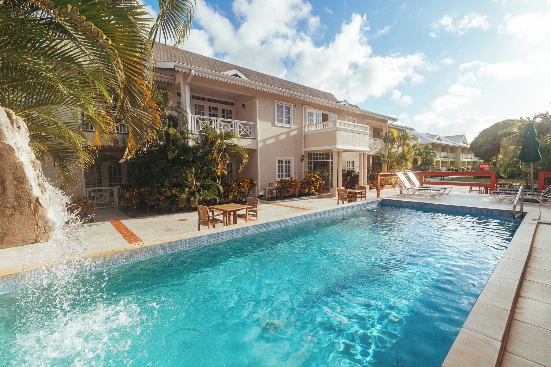 A resort with a swimming pool, outdoor seating, and a waterfall feature.