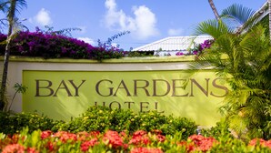 A sign for Bay Gardens Hotel surrounded by lush greenery and vibrant flowers. - Bay Gardens Hotel (Gros Islet)