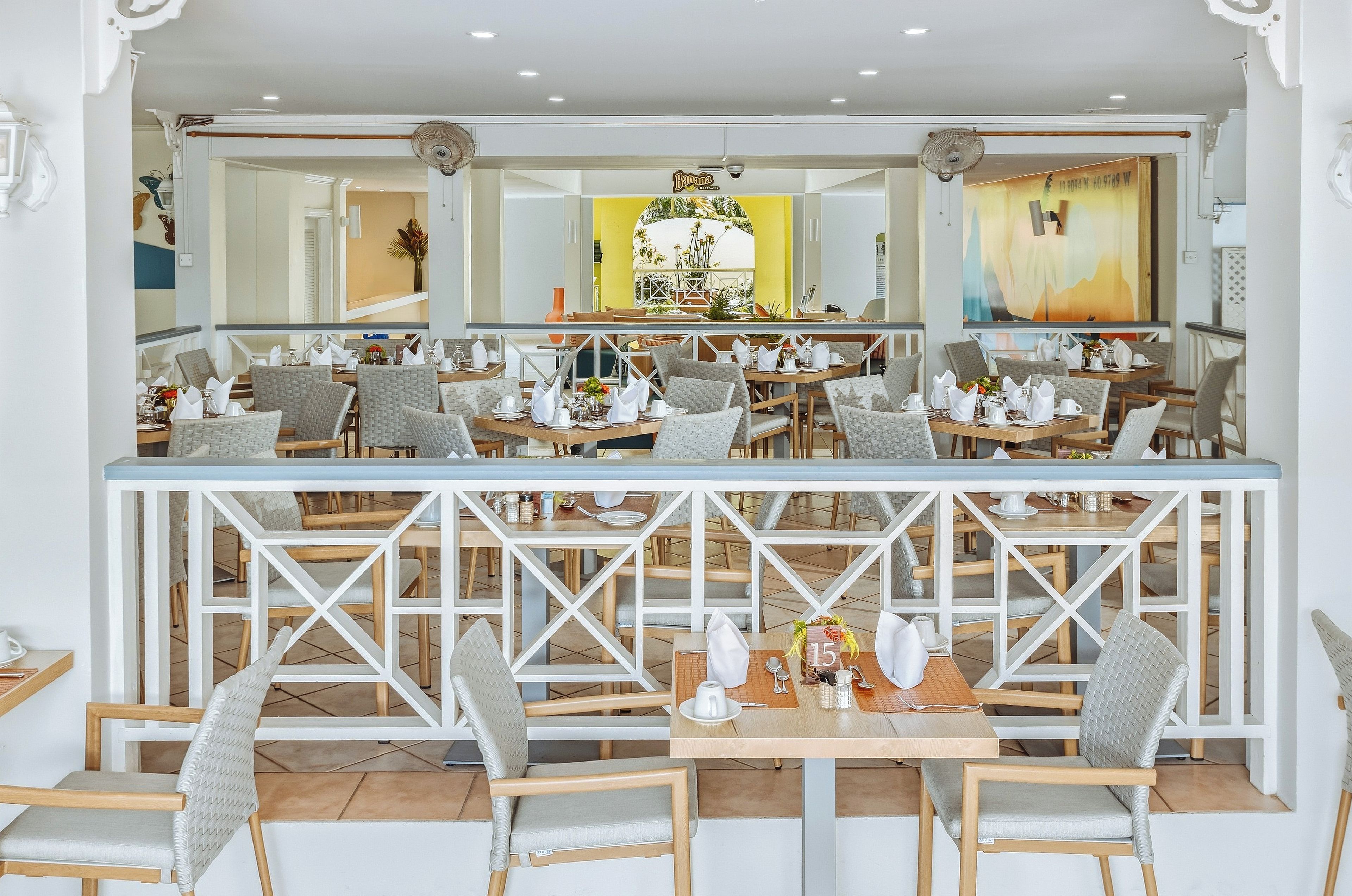 Un restaurante con varias mesas y sillas, una zona de bar central y vistas al exterior.
