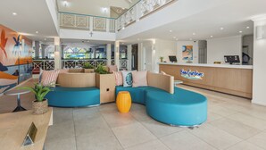 A hotel lobby with a reception desk, seating area, and a view of the bar area. - Bay Gardens Hotel (Gros Islet)