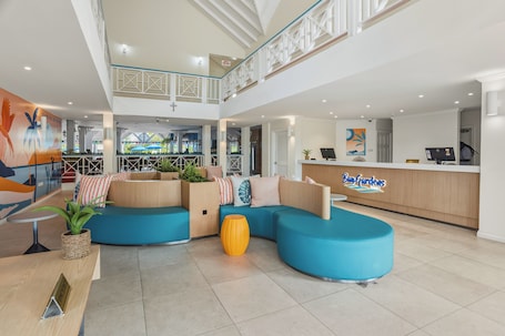Un hall de hotel con mostrador de recepción, zona de estar y vistas al área del bar.