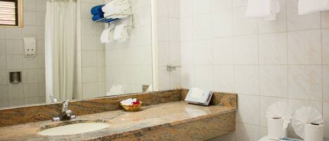 A bathroom with a granite countertop, a sink, a toilet, and a shower area.