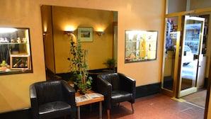 Un área de recepción con dos sillones de cuero negro, una mesa de madera y una planta en maceta.