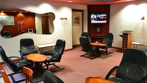 Una sala de conferencias con sillones de cuero, una pequeña mesa, una pantalla de televisión y un mapa en la pared.