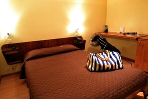 A hotel room with a bed, a nightstand, a desk, and a lamp. - Hotel Moderne Genève (Geneva)